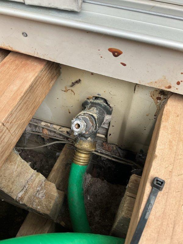 Replaced corroded outdoor spigot that had deteriorated and detached from the property. Installed new brass gate valve with star-shaped handle and secured all connections through the foundation access point beneath the exterior window. Tested system for proper water flow and verified no leaks at valve body, threaded fittings, or hose connection points.