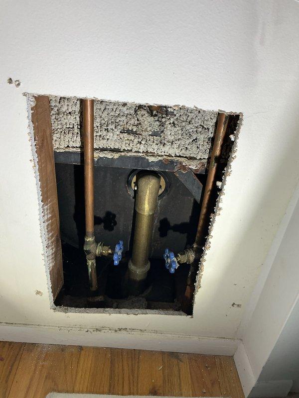 Responded to a dripping shower faucet in a second-floor bathroom of a 1970s-era home. Created access panel in wall to expose plumbing infrastructure and shut-off valves. Replaced worn shower valve assembly and cartridge that had been leaking for approximately two weeks. Addressed minor drip at bathroom sink faucet by replacing worn washers and seals. Installed new blue-handled shut-off valves on supply lines for improved future access and maintenance. Tested all fixtures for proper operation and verified no leaks present. Access panel left open for inspection, ready for drywall repair and finishing upon approval.