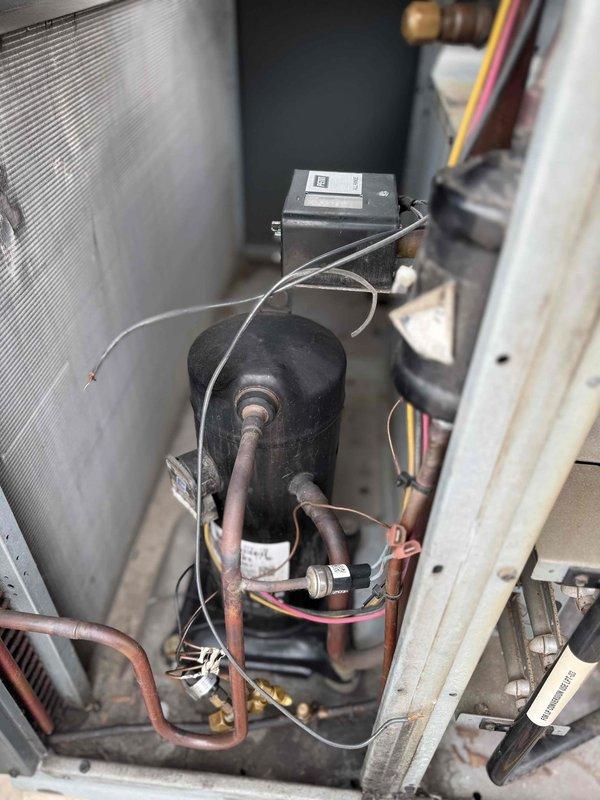 Responded to no cooling complaint on rooftop RTU unit with reported lack of airflow. Upon inspection, confirmed compressor and refrigerant system components present but identified potential blower motor failure preventing air circulation through the system. Accessed unit via ladder on commercial roof, documented internal mechanical components including compressor, control relay, heat exchanger coils, and associated refrigerant piping showing normal wear and oxidation consistent with unit age.