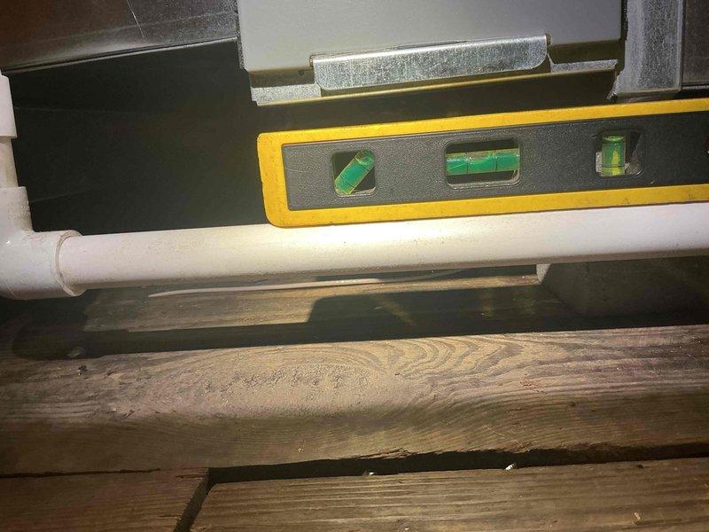 Responded to callback for newly installed AC system with no operation located in third floor attic. Upon inspection, found condensate drain line improperly pitched, causing potential drainage issues that may have contributed to system shutdown. Leveled and adjusted PVC condensate drain line to ensure proper pitch and drainage flow from air handler unit. Verified drain pan was dry and system returned to normal operation with adequate airflow restored.
