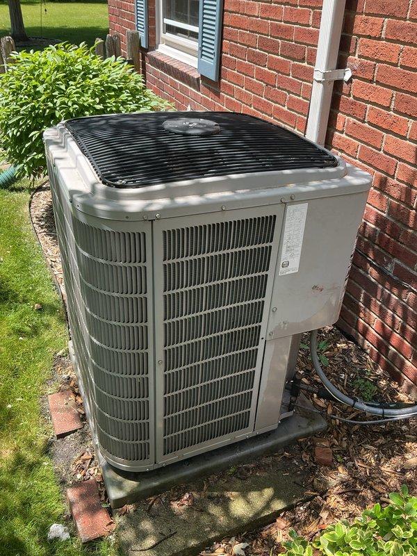 Completed comprehensive Gold AC Inspection on 17-year-old residential air conditioning system with outdoor condenser unit and basement air handler. Performed multi-point inspection including visual assessment of condenser unit exterior condition, verified proper installation on concrete pad, checked refrigerant line connections, inspected electrical conduit and connections, examined condensate drain line routing, and assessed overall system operation. Unit found to be functioning properly at time of inspection with no immediate service concerns identified. Condenser unit exterior shows normal wear consistent with age, surrounded by adequate clearance from landscaping for proper airflow. All accessible components inspected and documented photographically for service records.