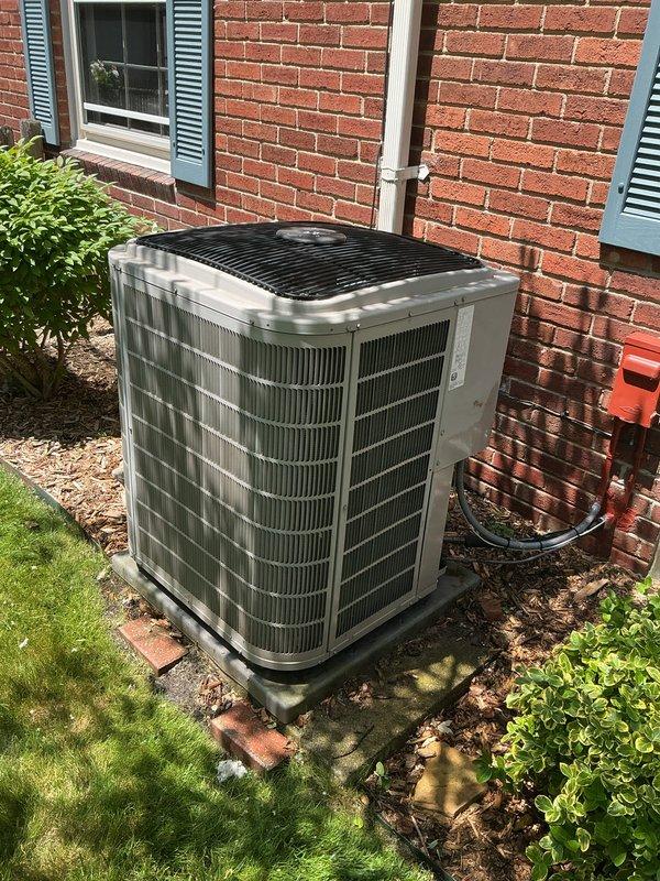 Completed comprehensive Gold AC Inspection on 17-year-old residential air conditioning system with outdoor condenser unit and basement air handler. Performed multi-point inspection including visual assessment of condenser unit exterior condition, verified proper installation on concrete pad, checked refrigerant line connections, inspected electrical conduit and connections, examined condensate drain line routing, and assessed overall system operation. Unit found to be functioning properly at time of inspection with no immediate service concerns identified. Condenser unit exterior shows normal wear consistent with age, surrounded by adequate clearance from landscaping for proper airflow. All accessible components inspected and documented photographically for service records.