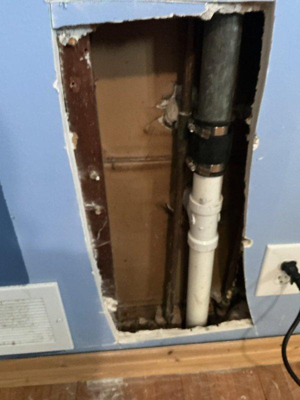Responded to plumbing repair call for moisture issues in crawl space and wall cavity access. Upon inspection, discovered compromised drainage system with visible standing water and saturated soil throughout crawl space area. White PVC drainage piping showed signs of potential leakage or inadequate drainage, contributing to excessive moisture accumulation beneath structure. 

Created wall access opening to expose and inspect concealed plumbing infrastructure. Located black supply line and white PVC drain line running vertically through wall cavity. Secured both pipes with proper mounting clamps to prevent movement and potential future damage. Addressed compromised wall section and prepared opening for proper plumbing access and future maintenance requirements.

Documented crawl space conditions showing moisture intrusion affecting floor joists and insulation integrity. Recommended ongoing monitoring of drainage system performance and crawl space moisture levels to prevent structural dam
