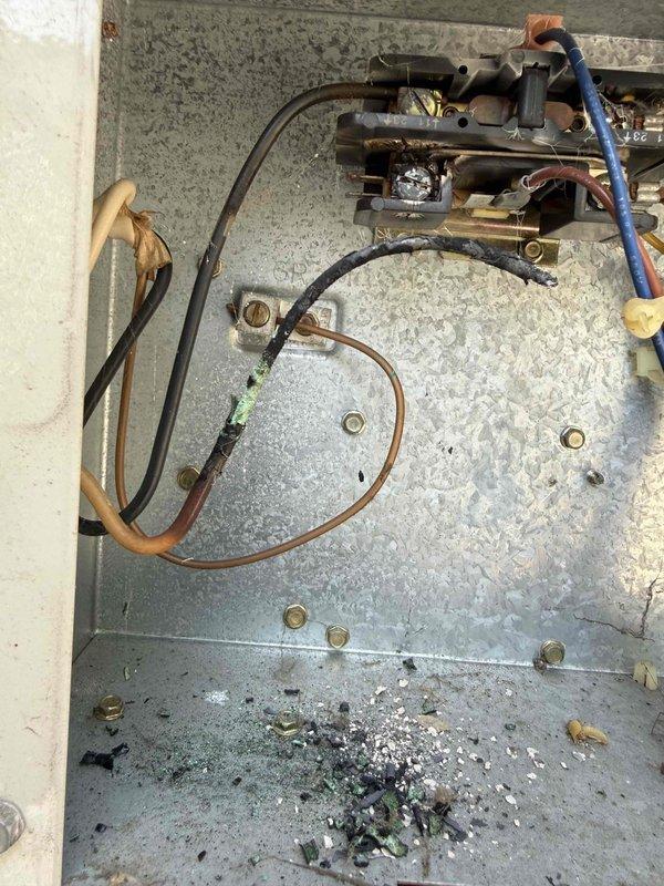 # HVAC No Cool Service Call

Responded to no cooling complaint on 10+ year old air conditioning system located in basement. Upon arrival, confirmed unit was not operating. Performed diagnostic inspection of outdoor condensing unit and indoor components. 

Visual inspection revealed significant debris accumulation inside electrical panel compartment, including dust, dirt, and deteriorated insulation material that had collected at bottom of enclosure. Examined contactor assembly, relay components, and associated wiring connections including black, blue, brown, and tan conductors. Checked copper refrigerant lines and electrical connections for proper operation.

Inspected outdoor unit mounting components and verified secure installation on exterior patio area. Examined electrical receptacle and mounting bracket assembly on top of condensing unit housing. All mounting hardware including hex bolts appeared secure with no visible damage to white cylindrical equipment housing.

Documented equ
