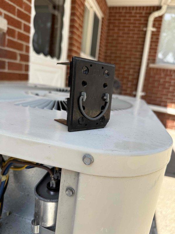 # HVAC No Cool Service Call

Responded to no cooling complaint on 10+ year old air conditioning system located in basement. Upon arrival, confirmed unit was not operating. Performed diagnostic inspection of outdoor condensing unit and indoor components. 

Visual inspection revealed significant debris accumulation inside electrical panel compartment, including dust, dirt, and deteriorated insulation material that had collected at bottom of enclosure. Examined contactor assembly, relay components, and associated wiring connections including black, blue, brown, and tan conductors. Checked copper refrigerant lines and electrical connections for proper operation.

Inspected outdoor unit mounting components and verified secure installation on exterior patio area. Examined electrical receptacle and mounting bracket assembly on top of condensing unit housing. All mounting hardware including hex bolts appeared secure with no visible damage to white cylindrical equipment housing.

Documented equ