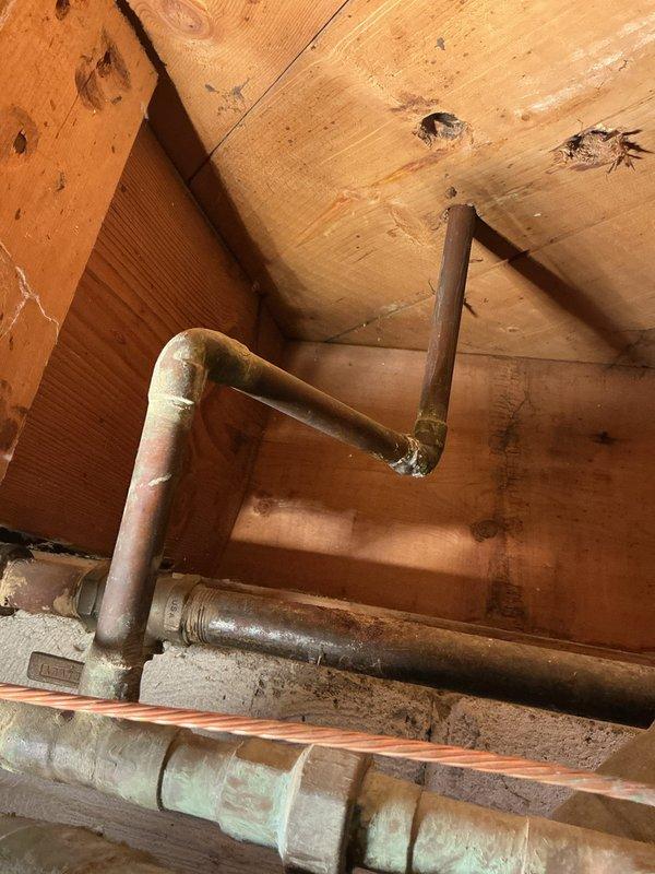 Replaced and rerouted copper plumbing lines in crawlspace area, installing new piping with properly fitted 90-degree elbow joints and compression fittings to navigate structural framing. Removed aging copper pipes showing significant oxidation and patina buildup, replacing them with new copper piping to ensure proper water flow and prevent future leaks in the confined space between ceiling joists.