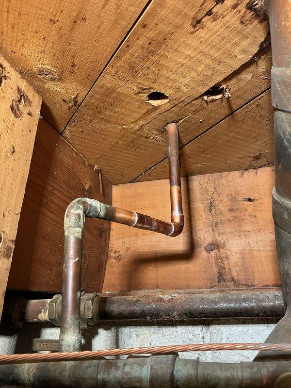 Replaced and rerouted copper plumbing lines in crawlspace area, installing new piping with properly fitted 90-degree elbow joints and compression fittings to navigate structural framing. Removed aging copper pipes showing significant oxidation and patina buildup, replacing them with new copper piping to ensure proper water flow and prevent future leaks in the confined space between ceiling joists.