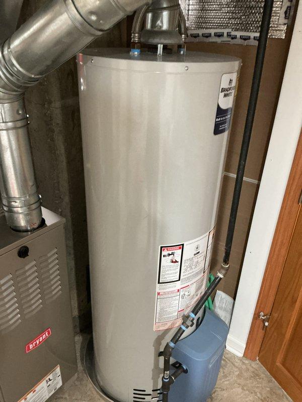 Completed comprehensive Gold AC inspection on residential cooling system under 10 years old with air handler located in basement. System confirmed operational and functioning properly at time of inspection. Inspected indoor air handler unit, ductwork connections, and outdoor condenser unit positioned on pad against exterior brick wall. Evaluated condenser cabinet condition, fan assembly operation, refrigerant line set, and electrical disconnect. Documented equipment configuration including water heater and furnace in mechanical room. Advised customer to maintain clear area around outdoor condenser unit, removing any debris or animal waste to ensure proper airflow and system efficiency.