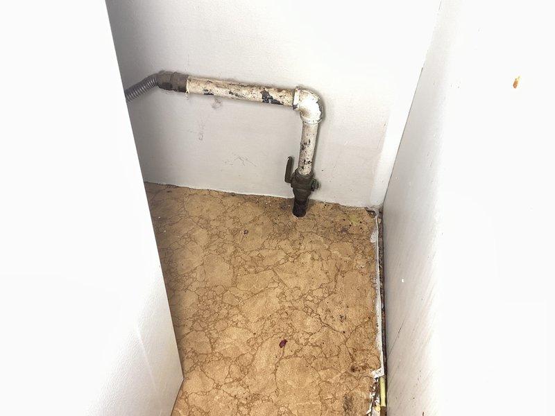 Responded to natural gas leak emergency behind kitchen oven after utility company confirmed leak and shut off gas supply to 1962-built home. Conducted thorough visual inspection of gas piping system in affected area, identifying severely corroded gas supply lines with compromised integrity due to age and deterioration. Documented existing conditions showing extensive rust and corrosion on vertical pipe assembly and fittings, with deteriorated paint coating exposing compromised metal surfaces. Assessed flexible gas connector to range and surrounding infrastructure for additional leak points and safety concerns.