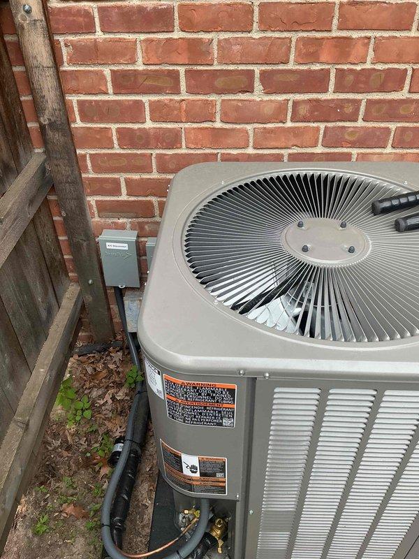 Responded to no-cooling call on 2-month-old residential AC system located in basement. Upon arrival, found outdoor condensing unit installed against brick wall with proper clearances and copper linesets in place. Investigated electrical connections at exterior disconnect and confirmed power supply to unit. Identified tripped breaker at electrical panel as root cause of system failure. Reset breaker, verified proper voltage at disconnect, and cycled system through complete operational test. Confirmed condenser fan motor operation, compressor startup, and normal amperage draw on all components. System restored to full cooling operation with no further issues detected.