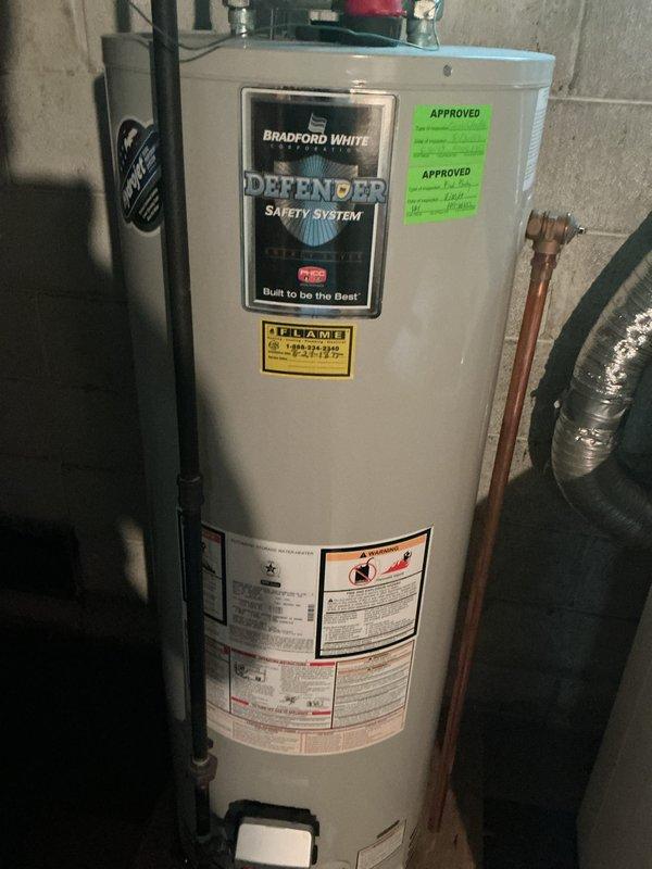 Completed comprehensive Gold AC inspection on residential cooling system under 10 years of age with air handler located in basement. Unit confirmed operational and performing within normal parameters. Inspected outdoor condenser unit positioned on concrete pad against brick exterior, noting satisfactory condition with proper clearances maintained. Evaluated indoor air handler and Bradford White water heater installation in basement utility area. Advised customer to maintain clear area around condenser unit, ensuring removal of debris and animal waste for optimal airflow and system efficiency.