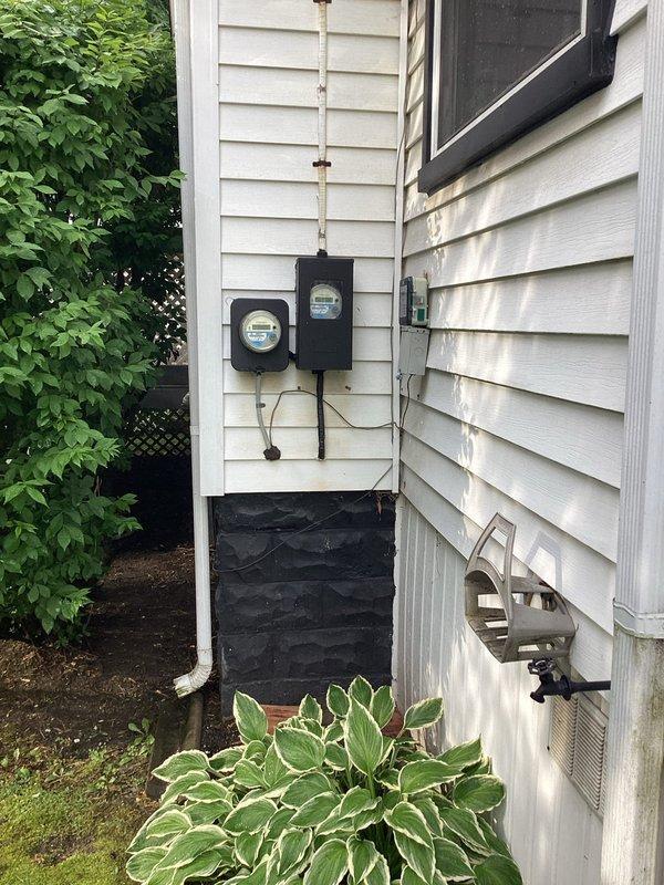 Conducted comprehensive assessment of 35-year-old residential HVAC system for complete replacement estimate. Evaluated outdoor air conditioning condenser unit positioned on concrete pad against exterior wall with existing electrical disconnect and PVC drainage, noting advanced age and condition of equipment. Inspected basement furnace installation, documented existing electrical service configuration with dual meter setup, and photographed current system components to provide accurate replacement specifications for both heating and cooling equipment.