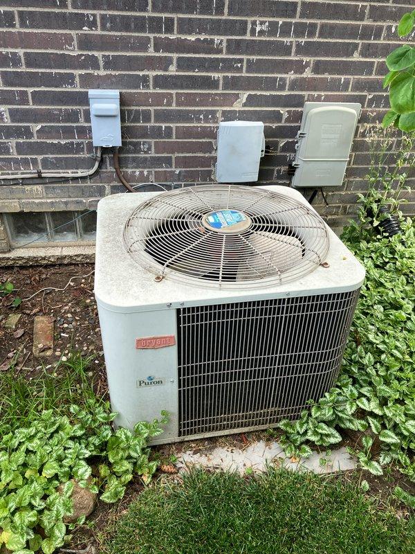 Conducted comprehensive assessment of existing 2003 Bryant/Payne air conditioning system showing partial functionality and significant aging. Unit located on exterior concrete pad displayed weathering, surface corrosion, and diminished performance typical of equipment exceeding 20-year service life. Evaluated basement-located natural gas furnace and exterior condensing unit, documenting equipment condition through photographic records. Observed exterior electrical service installation including utility meters and disconnect panels mounted on brick wall with visible efflorescence. Prepared detailed replacement estimate for complete HVAC system upgrade, accounting for existing infrastructure and accessibility considerations for installation crew.