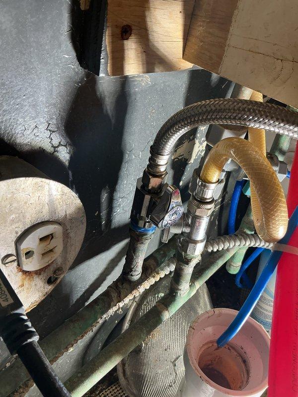 Completed commercial plumbing repair involving mechanical equipment and plumbing connections within an HVAC system utility cabinet. Serviced and repaired braided stainless steel flex lines, valve assemblies with colored handle components, and multiple flexible hose connections including rubber supply lines. Addressed plumbing fixture connections in confined mechanical space with deteriorated wall surfaces and aging infrastructure.