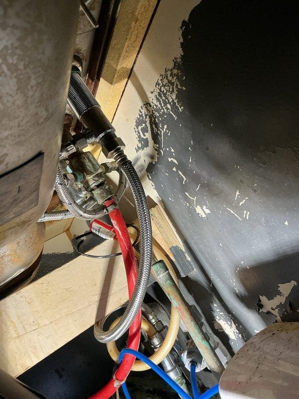 Completed commercial plumbing repair involving mechanical equipment and plumbing connections within an HVAC system utility cabinet. Serviced and repaired braided stainless steel flex lines, valve assemblies with colored handle components, and multiple flexible hose connections including rubber supply lines. Addressed plumbing fixture connections in confined mechanical space with deteriorated wall surfaces and aging infrastructure.