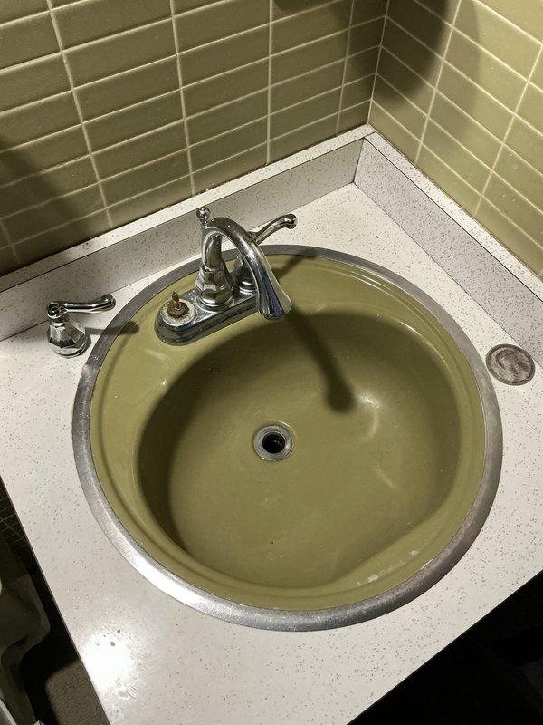 Responded to a broken bathroom faucet on the first floor of a 1968-built home. Upon inspection, found the existing chrome two-handle faucet mounted on a white speckled countertop with an olive-green basin was no longer functioning properly. Assessed the complete fixture assembly including under-sink plumbing connections and drain assembly. Provided recommendations for faucet replacement options compatible with the existing countertop configuration and advised the customer on purchasing a suitable replacement unit for future installation.