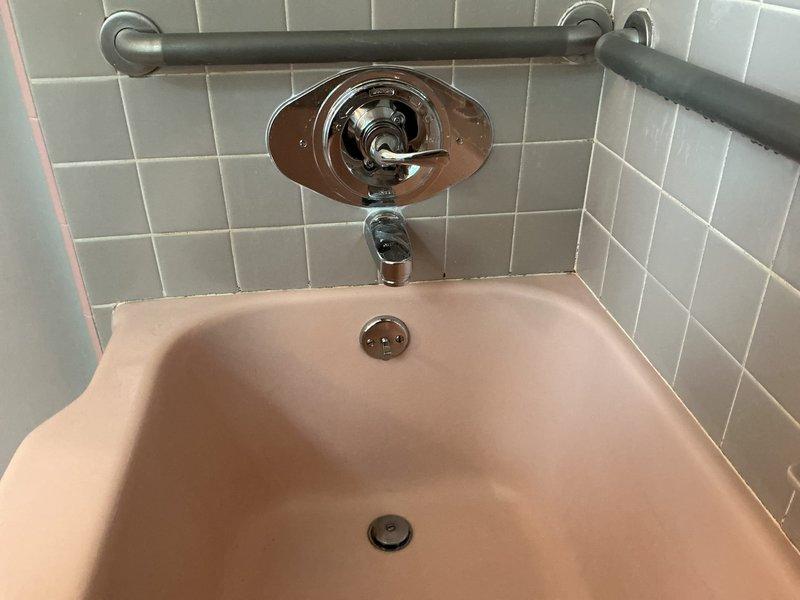 Replaced outdated three-handle shower valve with new Delta single-handle shower control valve in bathroom tub/shower installation. Accessed supply lines through floor cavity, shut off water supply using existing shut-off valves on copper piping, and completed valve installation with proper escutcheon plate mounting against white subway tile wall. Tested operation of new single-handle valve to ensure proper temperature control and water flow functionality.