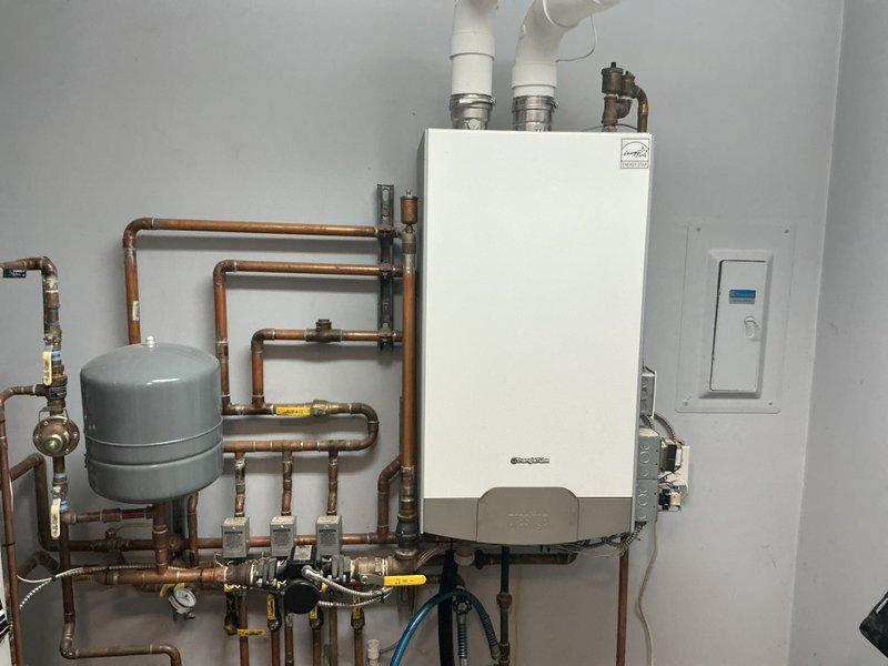 Conducted on-site evaluation for boiler replacement in residential basement mechanical room. Existing 15-year-old boiler system assessed, including current hydronic heating configuration with copper piping network, expansion tank, and associated plumbing components. Documented current installation layout featuring wall-mounted boiler unit with PVC exhaust/intake venting, multiple zone valves, pressure relief components, and connection points throughout the distribution system. Photographed existing equipment specifications, piping arrangements, and mechanical room conditions to prepare comprehensive replacement estimate for new boiler installation.