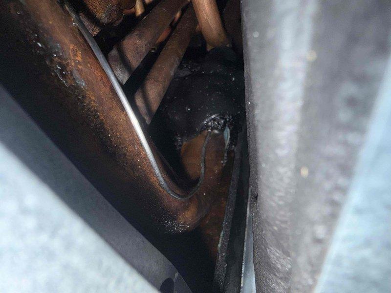 Responded to callback for condensate drain pan sensor continuously detecting moisture despite no visible water present after previous reset. Inspected evaporator coil assembly and drain pan components, noting moisture accumulation on copper refrigerant lines and surrounding metal components. TXV replacement part ordered and available at shop for follow-up installation to address underlying cooling performance issue causing unit to blow only slightly cool air.