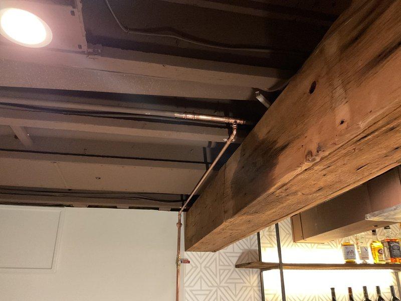 Completed plumbing repair work in basement utility area and adjacent bar/entertainment space. Installed and secured copper supply lines with proper mounting brackets to structural beams, ensuring code-compliant pipe support and clearance from ductwork and electrical systems. Verified proper water flow to utility sink fixture and tested all connections for leaks.