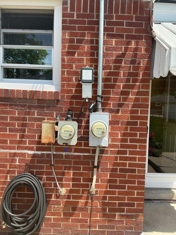 Provided replacement estimate for 28-year-old air conditioning and natural gas furnace system located in basement. Current equipment operational but nearing end of service life. Evaluated existing outdoor condenser unit positioned on concrete pad against exterior brick wall and assessed electrical service connections and refrigerant line routing for replacement specifications.