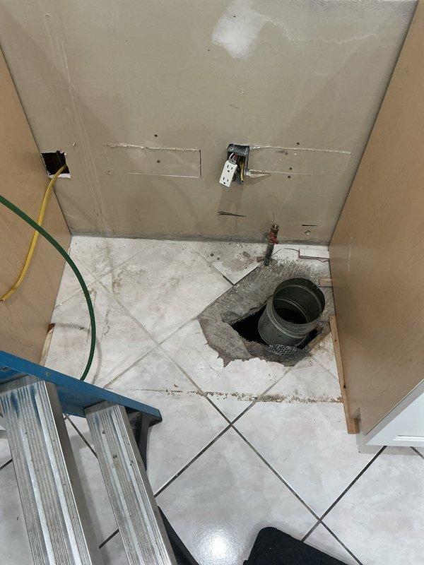 Responded to request for gas line relocation in kitchen to accommodate range stove installation in cabinet configuration. Reviewed available construction plans and specifications for 26-year-old home built in 2000. Accessed existing gas piping through floor opening, exposing copper pipe fitting and subflooring infrastructure. Assessed routing requirements for gas line relocation from current position to designated range location per cabinet layout specifications. Documented existing conditions including floor penetration, exposed piping components, and access point configuration for gas line modification work.