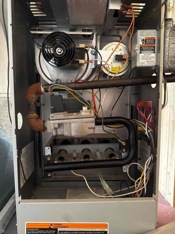 Performed comprehensive cooling maintenance on two 26-year-old HVAC systems per purchase agreement requirements. Completed full AC tune-up on both units, which were operational at time of service. Inspected furnace interior components including inducer motor, gas valve assembly, burner assembly, and heat exchanger; noted copper piping showing age-related oxidation on elbow joints. Evaluated outdoor condensing unit with protective wire guard on concrete pad. Both systems functioning properly throughout inspection, with maintenance performed due to equipment age and pending home warranty transfer to buyer.