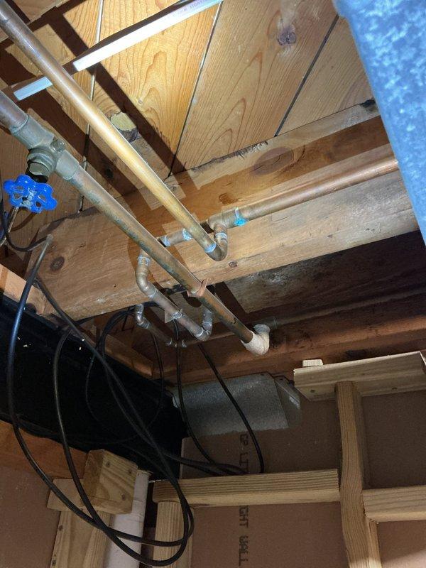 Responded to a leaky pipe issue in the basement of a 62-year-old residential property that had been ongoing for three weeks. Upon inspection, located the source of the leak in the galvanized steel supply line running through the floor joists in the basement ceiling area. The aging pipe showed signs of corrosion and deterioration consistent with the home's age, with active water seepage at a threaded connection point near a shutoff valve.

Shut off the main water supply and drained the affected section of the plumbing system. Removed the compromised galvanized pipe section and replaced it with new copper piping, including proper fittings and connections to ensure a watertight seal. Installed a new brass shutoff valve with green handle for improved accessibility and future maintenance. Secured all new piping with appropriate hangers and supports to the wooden joists to prevent stress on connections and minimize vibration.

Applied thermal insulation wrapping to the new copper pipe sectio