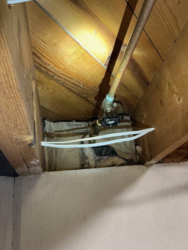 Responded to a leaky pipe issue in the basement of a 62-year-old residential property that had been ongoing for three weeks. Upon inspection, located the source of the leak in the galvanized steel supply line running through the floor joists in the basement ceiling area. The aging pipe showed signs of corrosion and deterioration consistent with the home's age, with active water seepage at a threaded connection point near a shutoff valve.

Shut off the main water supply and drained the affected section of the plumbing system. Removed the compromised galvanized pipe section and replaced it with new copper piping, including proper fittings and connections to ensure a watertight seal. Installed a new brass shutoff valve with green handle for improved accessibility and future maintenance. Secured all new piping with appropriate hangers and supports to the wooden joists to prevent stress on connections and minimize vibration.

Applied thermal insulation wrapping to the new copper pipe sectio