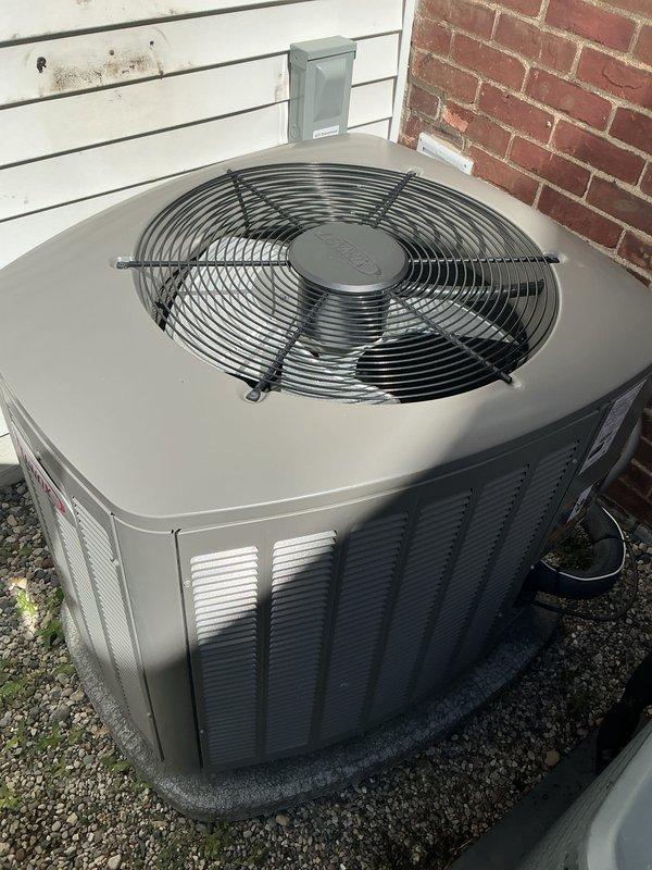 Completed comprehensive Gold AC inspection on dual-unit residential cooling system, both units approximately 3 years old with air handler/coil located in basement. Performed thorough evaluation of both outdoor condenser units, including Goodman brand unit, verifying proper operation, clearances, and ventilation access. Both systems confirmed operational with condensers properly positioned on concrete pads with adequate gravel drainage, clean exterior casings, unobstructed fan assemblies, and appropriate clearance from building structure for optimal airflow and serviceability.
