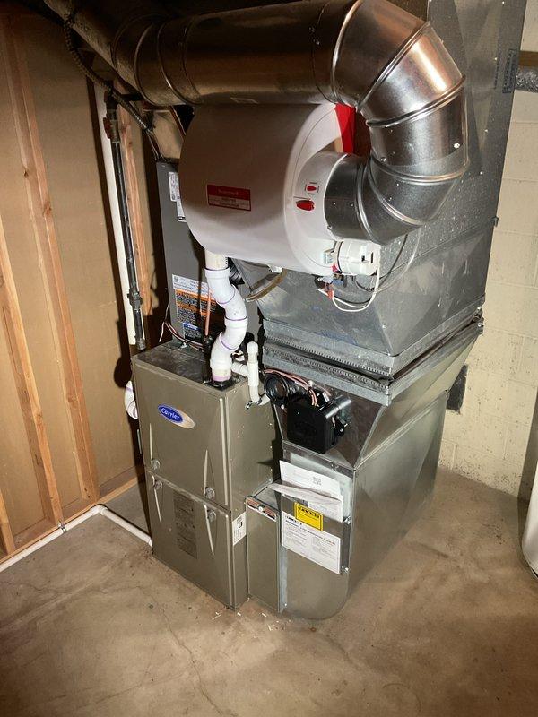 Completed full installation of 3-ton air conditioning system with evaporator coil in residential basement utility area. Installed new Carrier furnace unit with integrated A/C coil on concrete pad, connected to existing ductwork on right side configuration. Performed mechanical, electrical, and air conditioning connections including refrigerant line reconnection and proper sizing verification. Routed metallic ductwork with curved elbow joint for optimal airflow distribution. Secured all necessary permits for mechanical, electrical, and AC work. Verified proper clearances around water heater and utility equipment. Tested system operation and confirmed all connections meet code requirements.