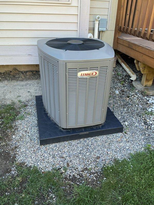 Completed comprehensive Gold Plan AC maintenance inspection on a one-year-old Lennox air conditioning system. Performed full tune-up service including inspection of outdoor condenser unit located on rubber pad between residential decks, verified proper installation on gravel base, checked refrigerant levels, cleaned condenser coils, tested electrical connections and capacitor function, and inspected indoor air handler unit in basement. All components found operating within manufacturer specifications with no deficiencies noted; system properly maintained and ready for cooling season.