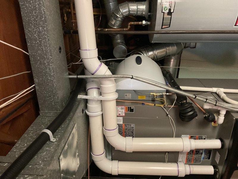 Completed full HVAC system installation including 90,000 BTU high-efficiency furnace and 3.5-ton air conditioning unit in rear yard location. Installed new thermostat, humidifier, base platform, and 600 CFM condensate pump with proper drainage piping. All PVC condensate lines properly primed and secured with multiple connection points routed through utility space. Air handler mounted with metallic supply and return ductwork including flexible and rigid sections with appropriate elbow transitions. System reconnected to existing infrastructure with all electrical connections completed and safety labels verified. Mechanical permit requested and AHRI certificate number 215665938 documented for utility rebate processing. All components tested and operational upon completion.