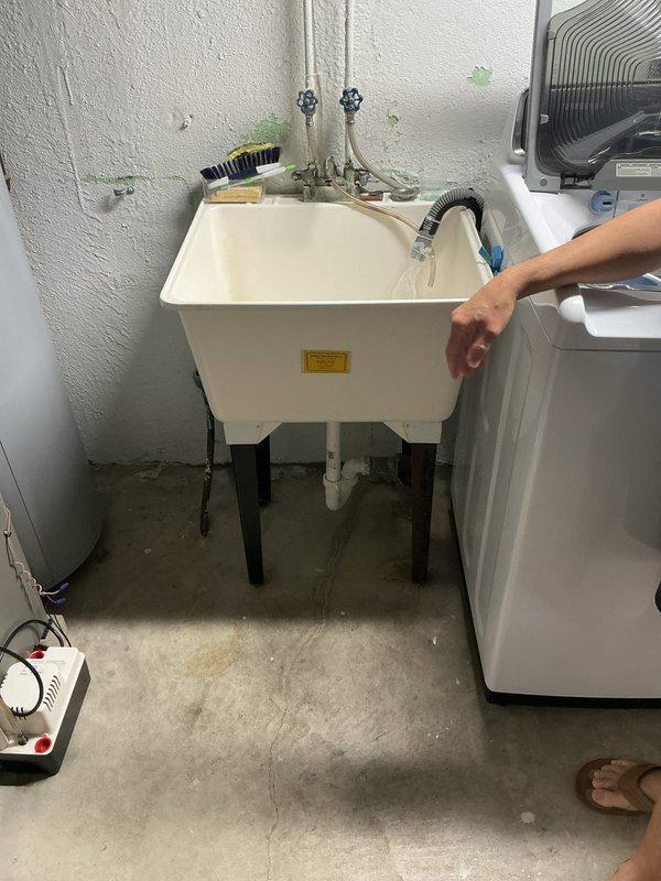 Provided comprehensive quote for utility sink replacement including new basin unit, faucet assembly, and cleanout drain installation. Assessed existing white utility sink mounted on black legs with chrome fixtures and flexible drainage components. Evaluated plumbing configuration in utility room adjacent to water heater and laundry appliances to determine scope of replacement work and material requirements.