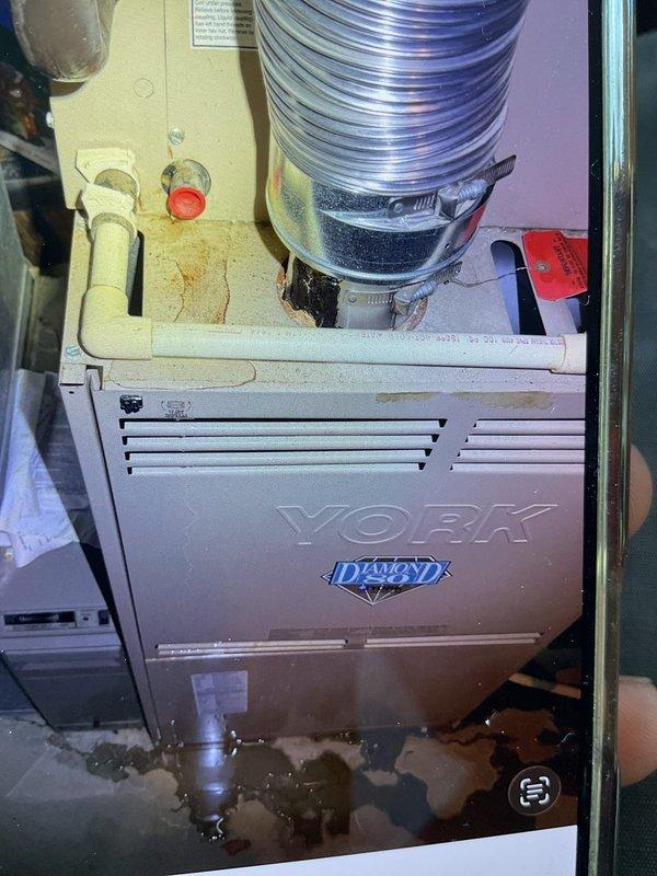 Responded to service call for non-operational cooling system with inoperative fan on 10+ year old YORK unit located on eastside of property. Upon arrival, discovered significant water accumulation at base of air handler indicating drainage system failure. Inspected condensate drain line and found complete blockage preventing proper drainage. Moisture patterns and discoloration on equipment panel confirmed ongoing condensation backup issue. Cleared condensate line obstruction and verified proper drainage flow. Tested system operation and confirmed fan motor and compressor cycling properly. System restored to normal cooling operation with adequate airflow throughout ductwork.