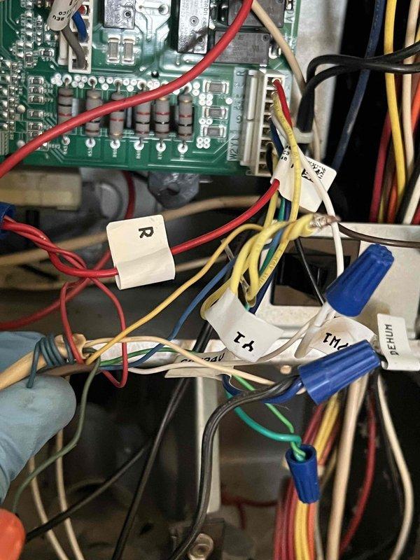 Responded to callback for ongoing air conditioning issue on 10+ year old system. Inspected control board and wiring connections following previous service visits by other technicians. Documented flame sensor circuit board and low-voltage wiring terminations with wire identification labels intact. Verified proper wire routing and connections at control board including R, Y1, and T1 terminals with secure wire nut connections. Provided technical assessment of system control components and clarified previous diagnostic findings to resolve conflicting repair recommendations.