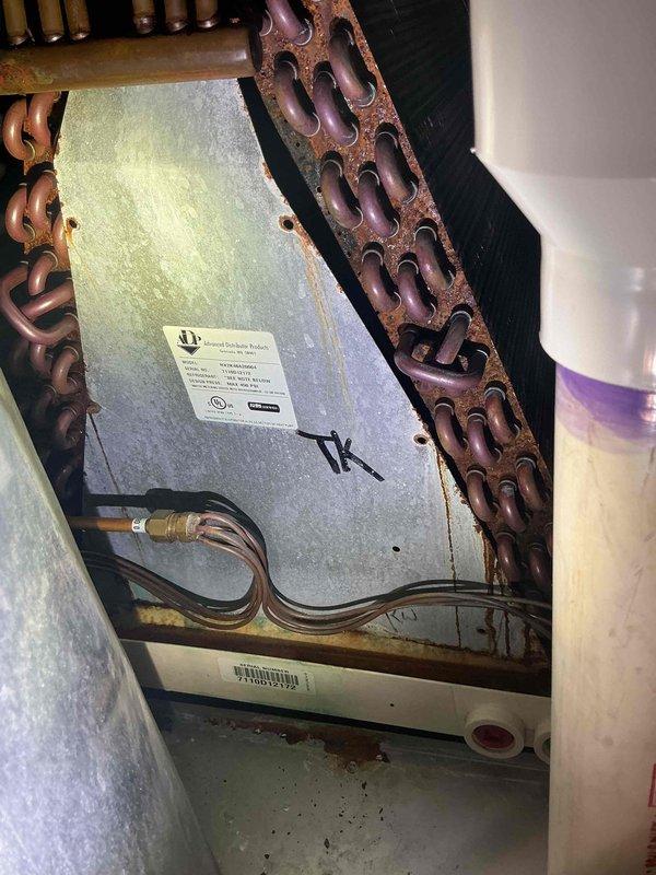 Responded to call for basement AC unit freezing up. Upon inspection, found evaporator coil experiencing ice buildup due to restricted airflow. Identified heavily corroded copper coil sections and deteriorated components showing significant oxidation and rust accumulation from moisture exposure. Assessed refrigerant lines, connections, and housing panels for integrity. Documented equipment condition with photos showing aged components, corroded coils, and compromised metal surfaces requiring attention to prevent continued freeze-up issues.