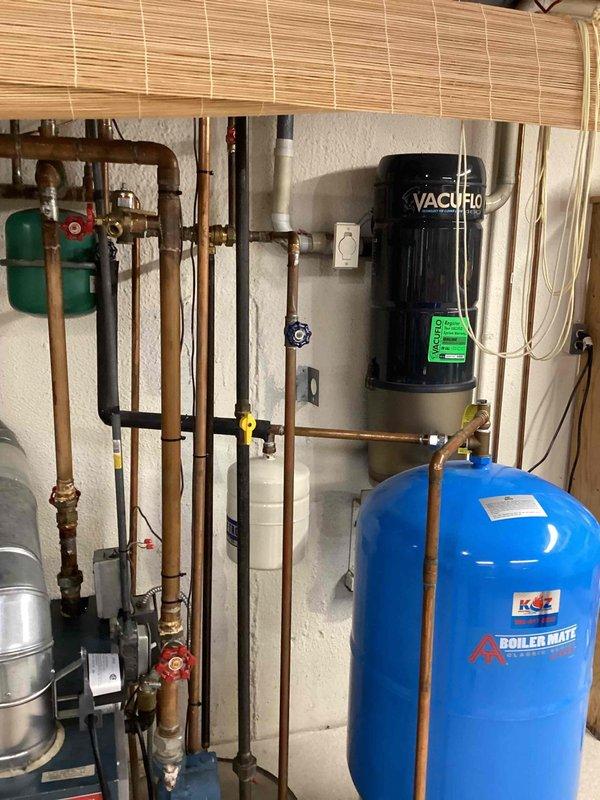 Provided estimate for indirect water heater installation in basement mechanical room. Evaluated existing hydronic heating system including expansion tank, circulation pump, and Boiler Mate pressure tank with associated copper piping and valves. Assessed current plumbing configuration and discussed indirect water heater integration options with existing boiler system infrastructure.