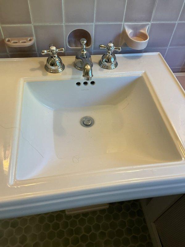 Responded to service call for bathroom sink with drainage issue. Upon inspection, found white rectangular basin sink with chrome three-piece faucet assembly and pop-up drain stopper mechanism experiencing complete drainage failure. Assessed drain assembly and stopper operation, cleared obstruction from drain line, and verified proper water flow and drainage function. Tested sink operation with hot and cold water supply to confirm full restoration of drainage capability.