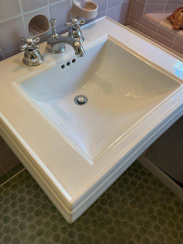 Responded to service call for bathroom sink with drainage issue. Upon inspection, found white rectangular basin sink with chrome three-piece faucet assembly and pop-up drain stopper mechanism experiencing complete drainage failure. Assessed drain assembly and stopper operation, cleared obstruction from drain line, and verified proper water flow and drainage function. Tested sink operation with hot and cold water supply to confirm full restoration of drainage capability.