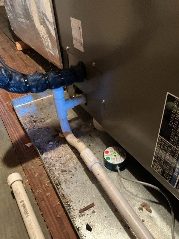 Completed comprehensive Gold AC Inspection on a two-year-old air conditioning system located on the upstairs porch. Performed full system tune-up including inspection of the air handler unit, verified thermostat operation showing 72°F setpoint with proper display functionality, checked condensate drainage system with blue PVC piping and flexible discharge line, and inspected all mechanical components. Verified Emerson programmable thermostat controls functioning correctly in cooling mode with auto fan settings. Examined equipment labels and specifications, confirmed all connections secure, and found system operating within normal parameters with no issues identified. Unit requires no immediate repairs and is ready for continued seasonal operation.