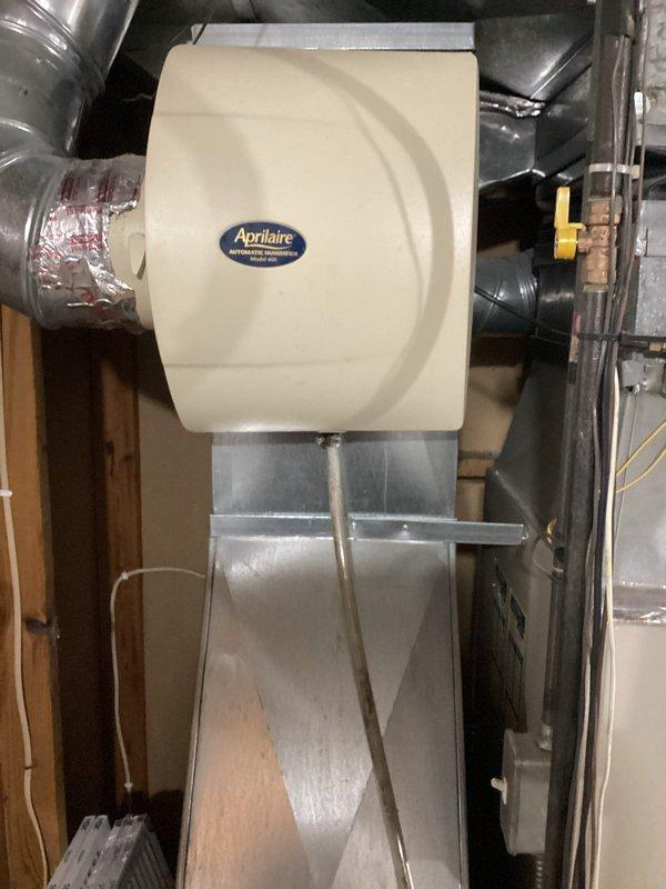 Completed comprehensive inspection of residential air conditioning system over 15 years old located at side of house with furnace in basement. Evaluated existing Luxaire furnace unit and associated HVAC components including Aprilaire automatic humidifier mounted on ductwork plenum. Assessed overall system condition, operational status, and equipment age to provide replacement estimate for aging AC unit and related mechanical systems.