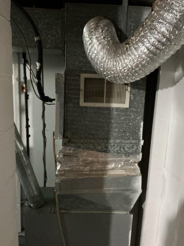 # HVAC System Evaluation and Estimate

Responded to service call for non-functional air conditioning system requiring full replacement assessment. Upon arrival, conducted comprehensive evaluation of existing HVAC installation located in confined utility closet space. Inspected current gray sheet metal air handler unit with connected flexible aluminum ductwork featuring S-shaped configuration. Noted existing system components including return air ductwork, wall-mounted return air grille, and electrical control wiring.

Performed thorough assessment of equipment condition, documenting significant dust and dirt accumulation on galvanized steel air handler exterior surfaces indicating extended operational use. Examined flexible ductwork connections, refrigerant line routing, and overall system configuration within tight installation space. Evaluated structural constraints of mechanical closet for replacement equipment specifications.

Photographed existing installation showing air handler 