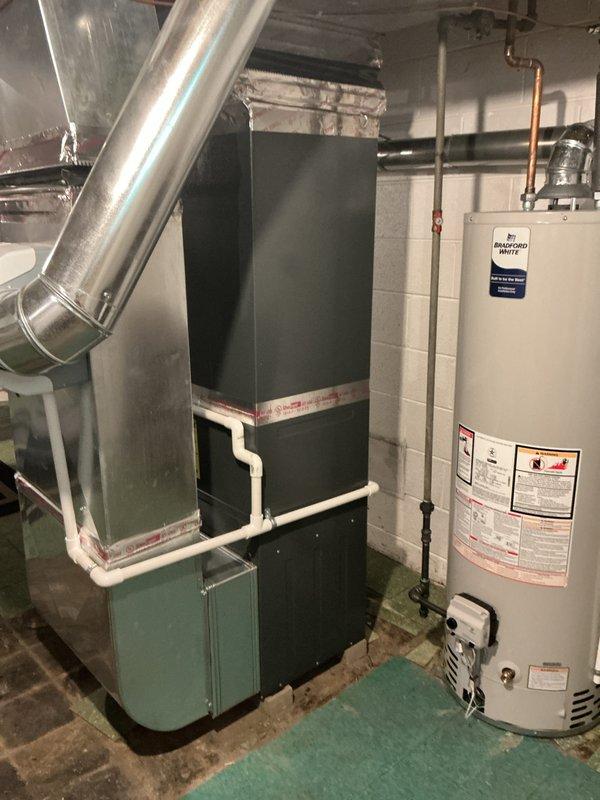 Completed comprehensive Gold AC inspection on 6-year-old residential HVAC system located in basement mechanical room. Performed full system evaluation including visual inspection of furnace, air handler, ductwork, refrigerant lines, and condensate drainage system. Verified equipment operational status, checked all electrical connections, examined humidifier unit, and assessed overall system condition. Documented equipment configuration with photographic records showing proper clearances and utility connections. All components found functioning normally with no immediate service requirements identified.