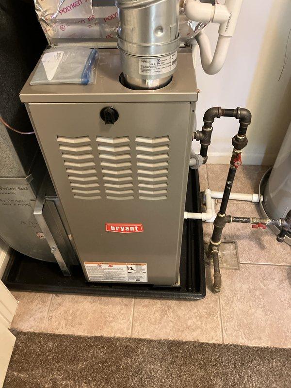 Conducted on-site evaluation for replacement estimate of twenty-year-old air conditioning system located outside downstairs front of residence. Documented existing HVAC equipment including Bryant furnace with gas piping and White Rodgers programmable thermostat. Captured photographic documentation of current system components to assess compatibility requirements and provide accurate replacement specifications for new air conditioner installation.