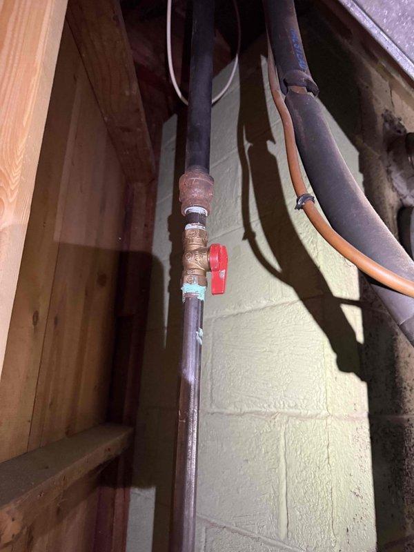 Responded to service call for reported water leak on 30-year-old furnace unit located in basement laundry room. Upon inspection, identified leaking from aged copper plumbing connections associated with the heating system. Inspected multiple vertical copper supply lines running through wall framing, noting significant oxidation and wear consistent with equipment age. Examined shut-off valve with red handle and associated brass fittings for integrity. Evaluated condition of pipe insulation, including deteriorated foam sections requiring attention. Performed electrical diagnostics on associated HVAC components using clamp meter to verify system operation and rule out condensate pump or humidifier issues as leak source. Documented existing plumbing configuration and leak location for repair recommendations given the advanced age of the equipment and infrastructure.