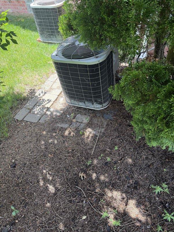 Completed comprehensive Gold AC inspection on 25-year-old residential air conditioning system with air handler located in basement and dual outdoor condenser units. Performed full system evaluation including visual inspection of both outdoor condensers, which showed accumulation of debris and organic material on surrounding ground area and unit surfaces. Inspected basement mechanical equipment and plumbing connections, noting mineral deposits and discoloration around water heater pan area indicating previous moisture issues. Documented system condition through photographic records showing outdoor unit placement in landscaped area with adequate clearance and indoor mechanical components. System operational at time of inspection with homeowner present to discuss findings and maintenance recommendations for aging equipment.