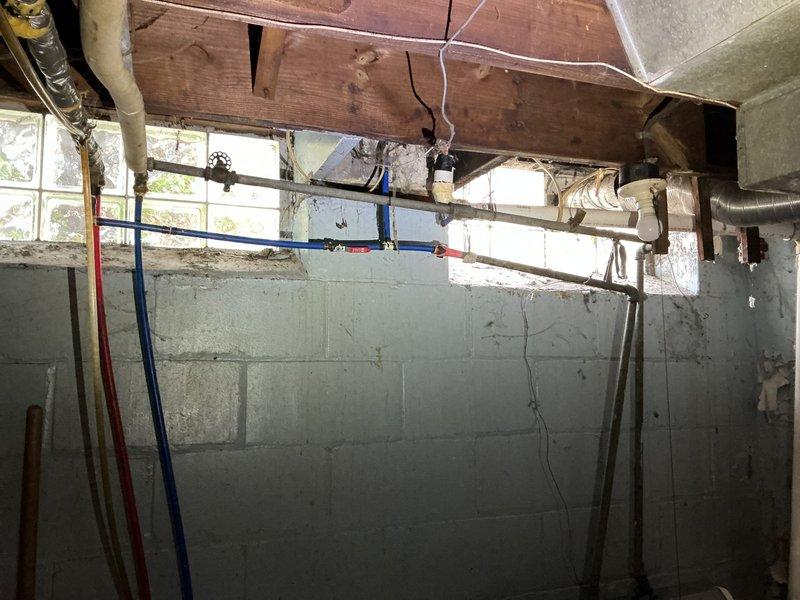 Conducted comprehensive whole-home replumbing assessment in response to free estimate request. Inspected existing plumbing infrastructure throughout property, including crawl space and basement areas, documenting current piping conditions. Evaluated aging copper supply lines, white PVC drain-waste-vent system, and blue PEX water distribution lines running through floor joists and ceiling cavities. Identified mixed-age plumbing materials requiring replacement, including deteriorated metallic piping and older PVC connections with visible wear. Assessed structural penetrations through wooden floor joists and concrete block foundation walls, noting proper clearances and support bracket installations. Photographed existing pipe routing, junction points, and accessibility for future replumbing work. Provided detailed estimate for complete residential replumbing project to modernize water distribution system and ensure code compliance.