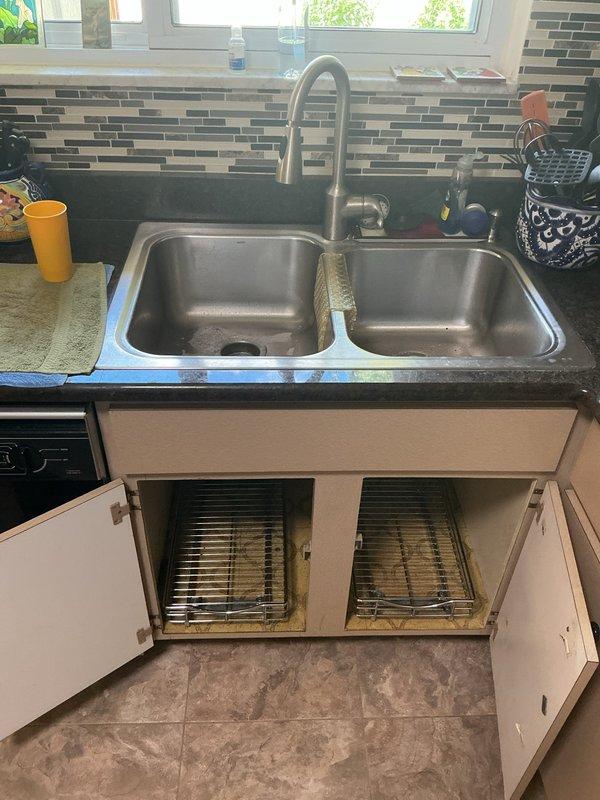 Responded to recurring kitchen sink clog in 1960s-era home with double-basin stainless steel sink and PVC P-trap configuration. Cleared obstruction from drain line and inspected under-sink plumbing assembly, noting existing water staining on cabinet interior indicating potential previous leak history. Advised customer on preventive maintenance given repeat occurrence within one-week timeframe and recommended monitoring drain performance closely due to age of home's plumbing system.