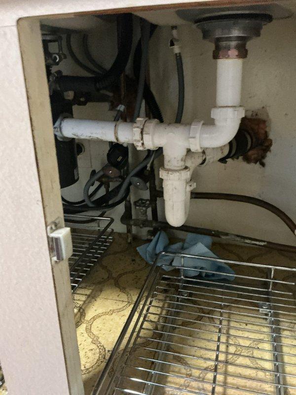 Responded to recurring kitchen sink clog in 1960s-era home with double-basin stainless steel sink and PVC P-trap configuration. Cleared obstruction from drain line and inspected under-sink plumbing assembly, noting existing water staining on cabinet interior indicating potential previous leak history. Advised customer on preventive maintenance given repeat occurrence within one-week timeframe and recommended monitoring drain performance closely due to age of home's plumbing system.